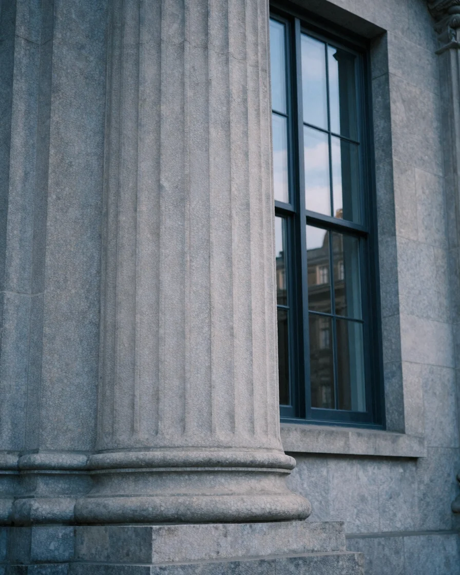 Close architectural detail of a stone courthouse column and tall window in soft diffuse daylight, midnight-blue and cool